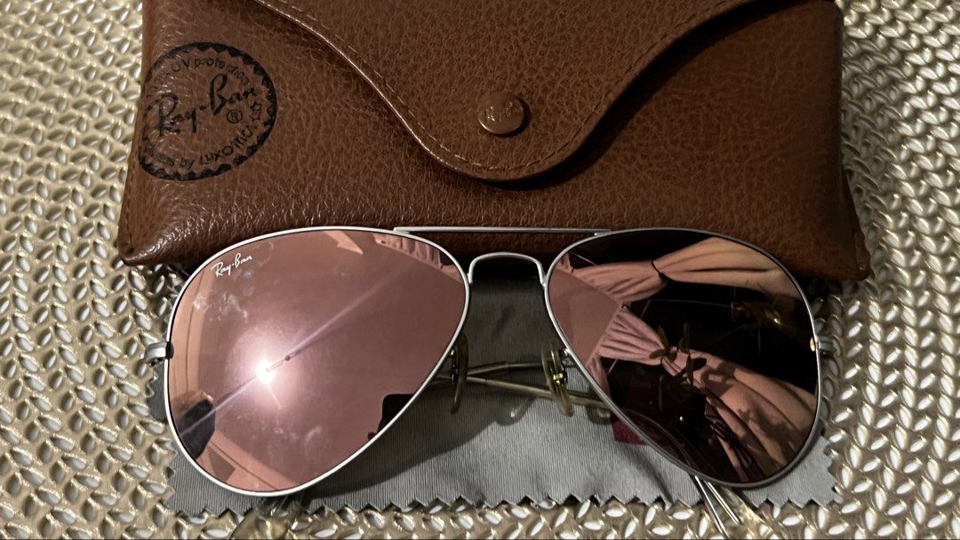 Ray-Ban Aviator Sunglasses (Category: Sunglasses & Eyewear) located in Manila. Submitted by skin_care_depot (Listing ID 1466309233, Image 1). Description: Ray-Ban aviators with rose gold mirrored lenses and silver metal frames. Iconic teardrop shape. Includes brown leather hard case stamped with the Ray-Ban logo and a grey cleaning cloth with red branding. Lenses clean, hinges tight, minimal wear overall. Authentic Rayban Aviator, used but not ab