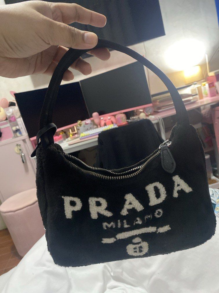 Re edition Terry Mini Bag (Category: Luxury Bags & Wallets) located in Davao. Submitted by sheymei (Listing ID 1466200197, Image 2). Description: • Material: Soft terry cloth fabric with a fuzzy texture. • Design: Features the distinctive embroidered Prada Milano logo on the front. • Hardware: Silver-tone zipper closure and a matching fabric top handle. • Details: Includes a detachable leather key ring enclosed in a small pouch.