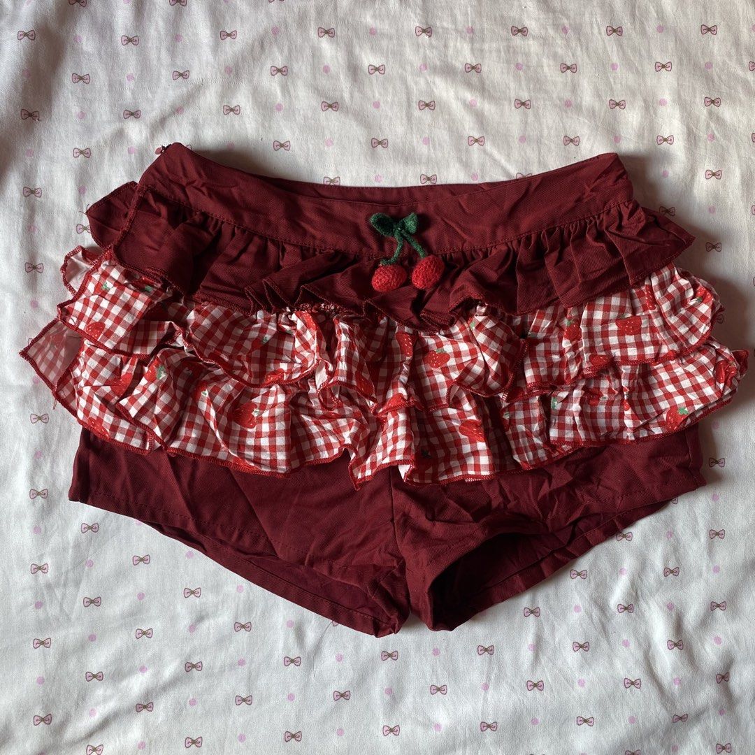 Red Gingham Strawberry Ruffle Shorts with Cherry Charm (Category: Shorts) located in Abulug. Submitted by dear_darlingdoll (Listing ID 1466287551, Image 1). Description: Maroon shorts with layered red and white gingham strawberry print ruffles. Small felt cherry charm pinned on the front waistband. Side zipper closure. Tag says size S. Hand wash only, no bleach, do not tumble dry. Fun coordinates for sweet casual outfits..