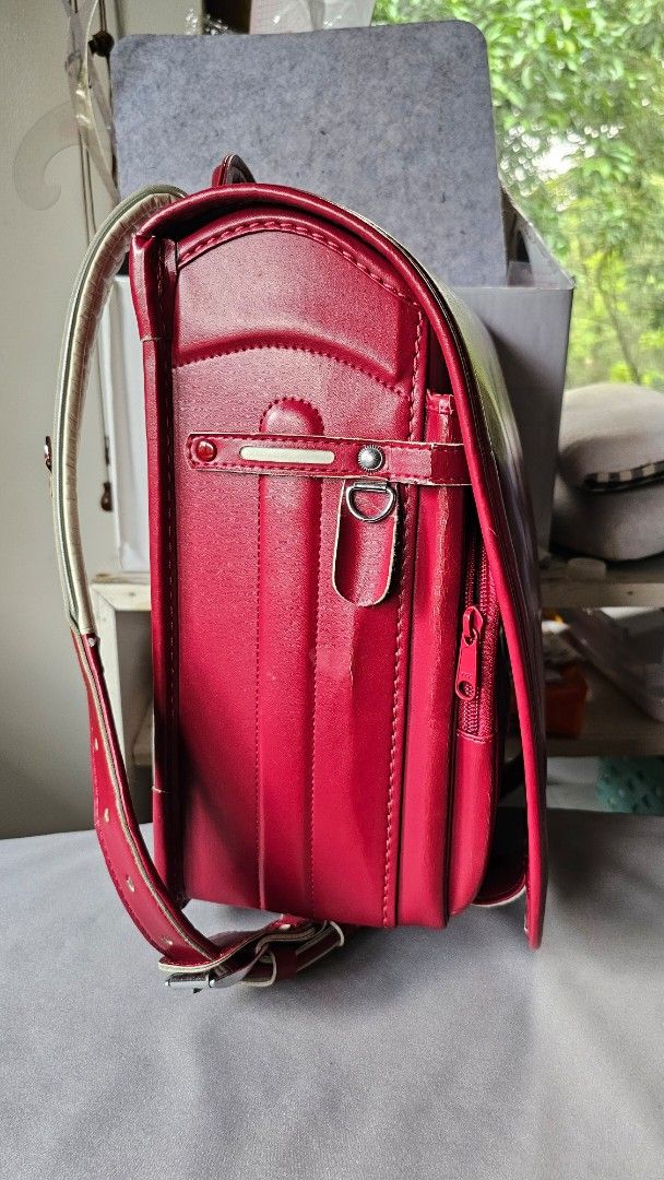 Red Japanese Randoseru School Backpack (Category: Backpacks) located in Quezon. Submitted by cgmhe (Listing ID 1466180856, Image 3). Description: Traditional Japanese randoseru school bag in deep red. Sturdy structured leather-like design with a flap closure, metal clasp hardware, and white padded shoulder straps. Built with multiple compartments and side D-rings. Classic boxy shape holds books and daily gear securely. Used condition with minor s