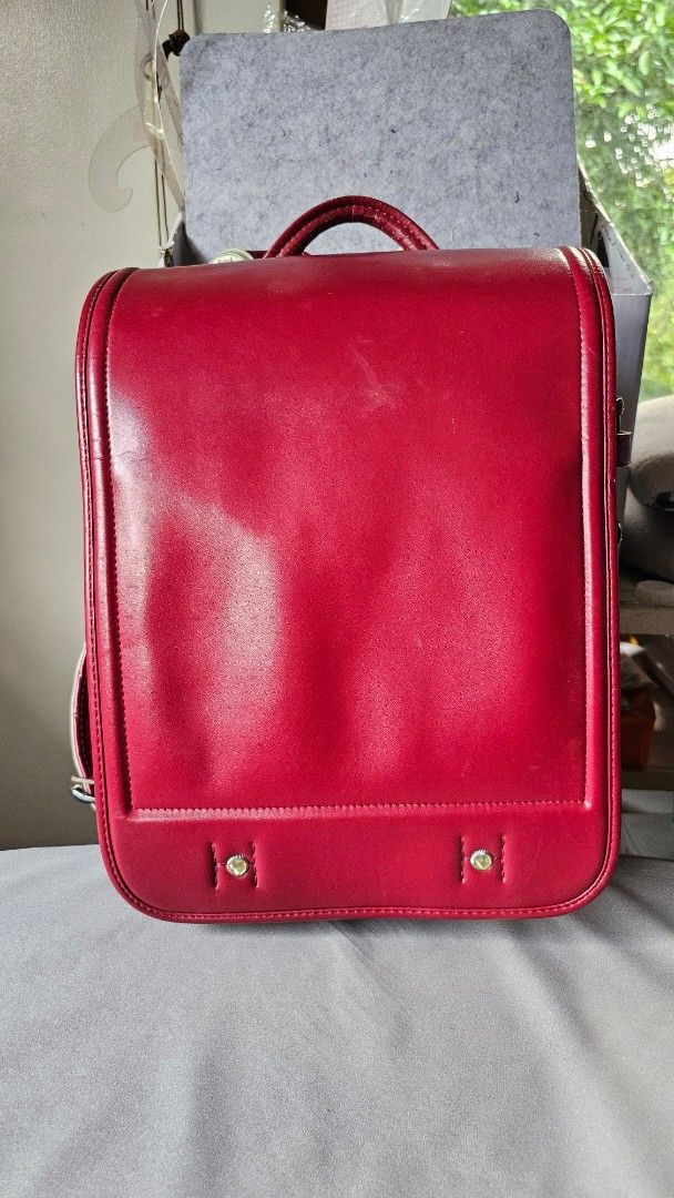 Red Japanese Randoseru School Backpack (Category: Backpacks) located in Quezon. Submitted by cgmhe (Listing ID 1466180856, Image 2). Description: Traditional Japanese randoseru school bag in deep red. Sturdy structured leather-like design with a flap closure, metal clasp hardware, and white padded shoulder straps. Built with multiple compartments and side D-rings. Classic boxy shape holds books and daily gear securely. Used condition with minor s