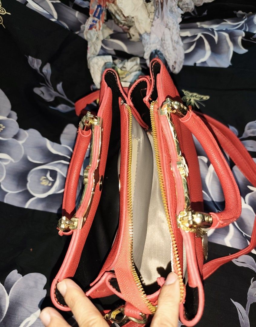 Red structured handbag with charm and shoulder strap (Category: Tote Bags) located in Bulacan. Submitted by gelvy1316 (Listing ID 1466254259, Image 3). Description: - Color: Vibrant red with chic gold-tone hardware - Design: Textured material featuring a dainty white floral charm on the handle - Interior: Light-colored fabric lining with a convenient center zipped divider for easy organization - Strap: Includes a matching adjustable shoulder stra