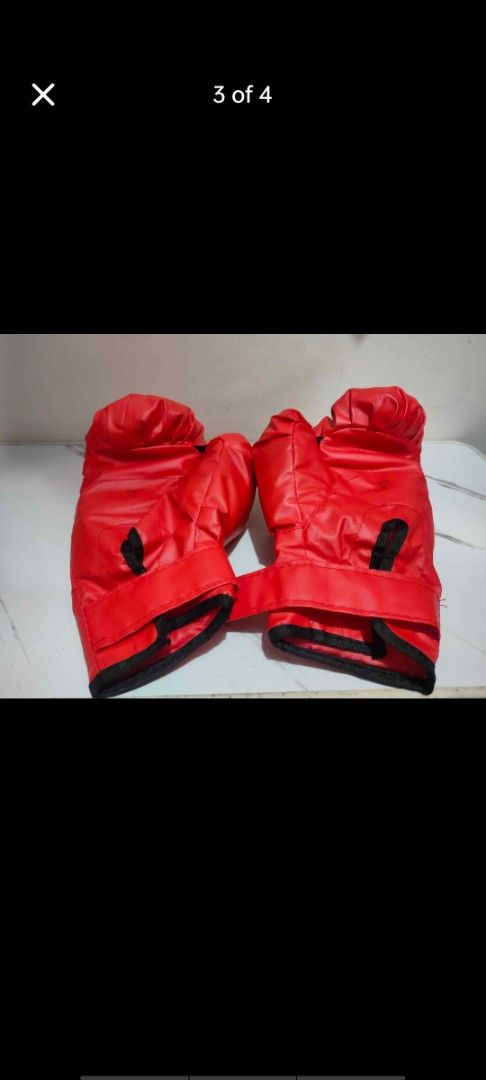 Red training boxing gloves with wrist strap (Category: Combat Sports) located in Manila. Submitted by billythekid05 (Listing ID 1466278328, Image 3). Description: - Vibrant red boxing gloves made of durable synthetic leather - Features soft padding for comfortable hand protection - Secure velcro wrist strap closure with stylish black trim - Impeccable, clean condition with zero scuffs or marks - Ideal for fitness workouts, mitt work, and heavy ba