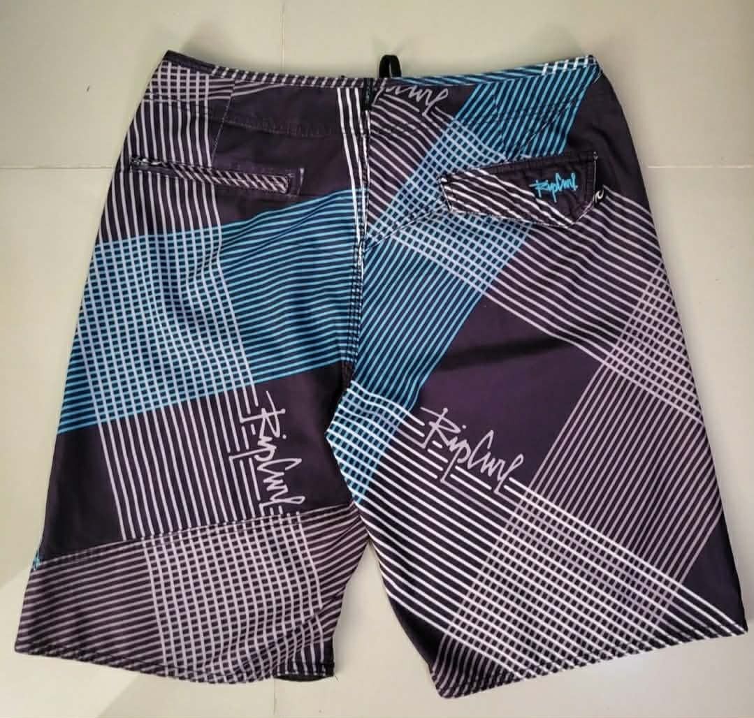 Rip Curl Plaid Boardshorts Swim Trunks (Category: Swim Trunks & Board Shorts) located in Bulacan. Submitted by clutsngo (Listing ID 1466185499, Image 2). Description: -450php shipped - Brand: Rip Curl - Style: Boardshorts / Surf wear - Design: Dark purple, blue, and white geometric plaid pattern - Details: Drawstring closure with branded eyelets and interior woven waist tag - Storage: Small back right pocket with flap closure - Branding: Embroide