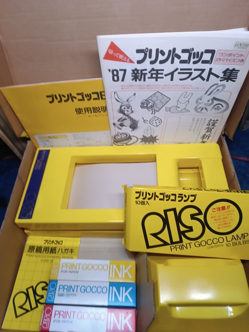 Riso Print Gocco B6 Set Printer (Category: Printers, Scanners & Copiers) located in Manila. Submitted by naneropane48426 (Listing ID 1466276586, Image 1). Description: Complete Riso Print Gocco B6 set in original box. Includes yellow printer unit, unopened box of 10 lamps, three tubes of print ink, instruction manual, postcard drawing papers, and the 1987 New Year illustration book. Yellow storage box has some vintage wear on the outside..