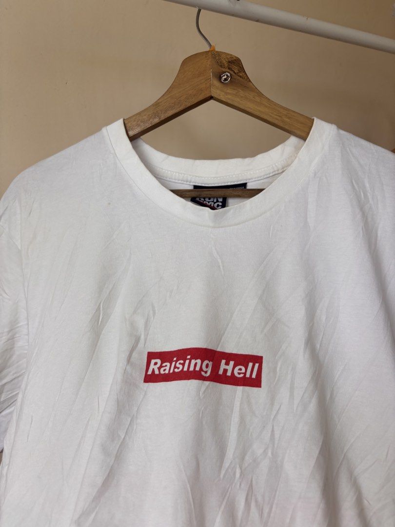 Run DMC Raising Hell White T-Shirt (Category: Tshirts & Polo Shirts ) located in Andop. Submitted by ukaylangpo (Listing ID 1466193439, Image 3). Description: - Item: White Run DMC Graphic Tee - Size: Tagged M/M (Measures approx. 23-24 inches across the chest) - Design: Small red 'Raising Hell' box logo on front, large black & white band photo with 'Raising Hell' banner on back - Fit/Material: Standard fit, comfortable cotton fabric.