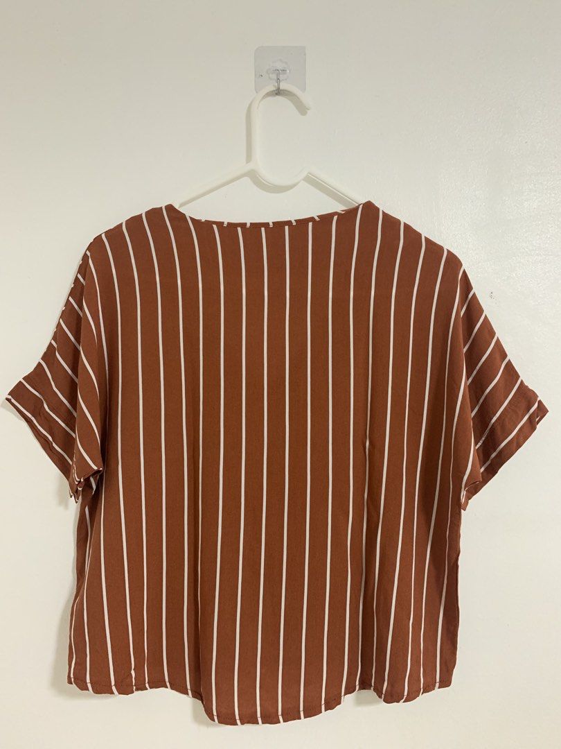Rust Brown Striped V-Neck Short Sleeve Blouse (Category: Blouses) located in San Pedro. Submitted by reginacarla (Listing ID 1466175481, Image 2). Description: - Color & Pattern: Rust brown with white vertical stripes - Neckline: V-neck with two front buttons - Fit & Style: Relaxed fit with a high-low curved hem and short sleeves - Fabric: Lightweight and breathable for warm weather - Versatility: Easy to style with your favorite denim jeans or s