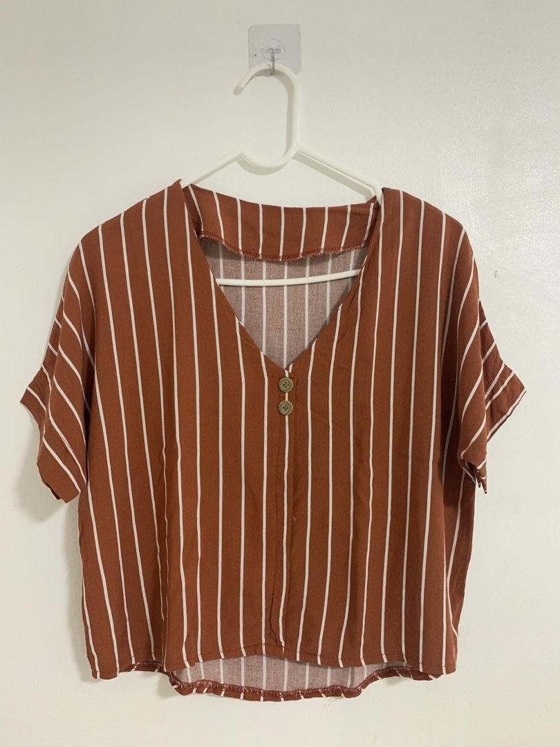Rust Brown Striped V-Neck Short Sleeve Blouse (Category: Blouses) located in San Pedro. Submitted by reginacarla (Listing ID 1466175481, Image 1). Description: - Color & Pattern: Rust brown with white vertical stripes - Neckline: V-neck with two front buttons - Fit & Style: Relaxed fit with a high-low curved hem and short sleeves - Fabric: Lightweight and breathable for warm weather - Versatility: Easy to style with your favorite denim jeans or s