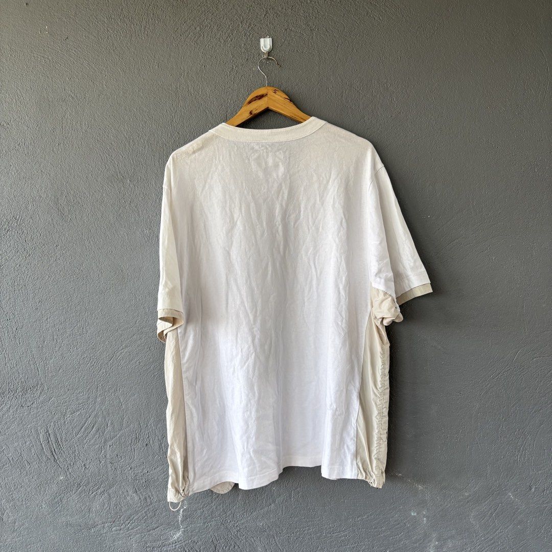 Sacai tee (Category: Tshirts & Polo Shirts ) located in San Fernando. Submitted by diff.thr1ft (Listing ID 1466170739, Image 2). Description: - Brand: Sacai - Color: White with beige layered panels - Material: 100% Cotton body with polyester attached parts - Features: Chest pocket, unique functional side zipper pockets - Origin: Made in Japan - Condition: Excellent pre-owned condition Fit large to xl.