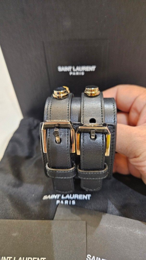 Saint Laurent Black Leather Studded Cuff Bracelet (Category: Luxury Accessories) located in Pasig City. Submitted by krist1na092 (Listing ID 1466315571, Image 3). Description: SAINT LAURENT PARIS WIDE STUDDED LEATHER CUFF Statement Saint Laurent Paris bracelet crafted in black leather with gold-tone stud hardware, featuring a bold double-strap construction and dual buckle closure. A striking discontinued Saint Laurent design with the edgy rock-in