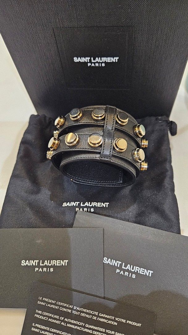 Saint Laurent Black Leather Studded Cuff Bracelet (Category: Luxury Accessories) located in Pasig City. Submitted by krist1na092 (Listing ID 1466315571, Image 2). Description: SAINT LAURENT PARIS WIDE STUDDED LEATHER CUFF Statement Saint Laurent Paris bracelet crafted in black leather with gold-tone stud hardware, featuring a bold double-strap construction and dual buckle closure. A striking discontinued Saint Laurent design with the edgy rock-in
