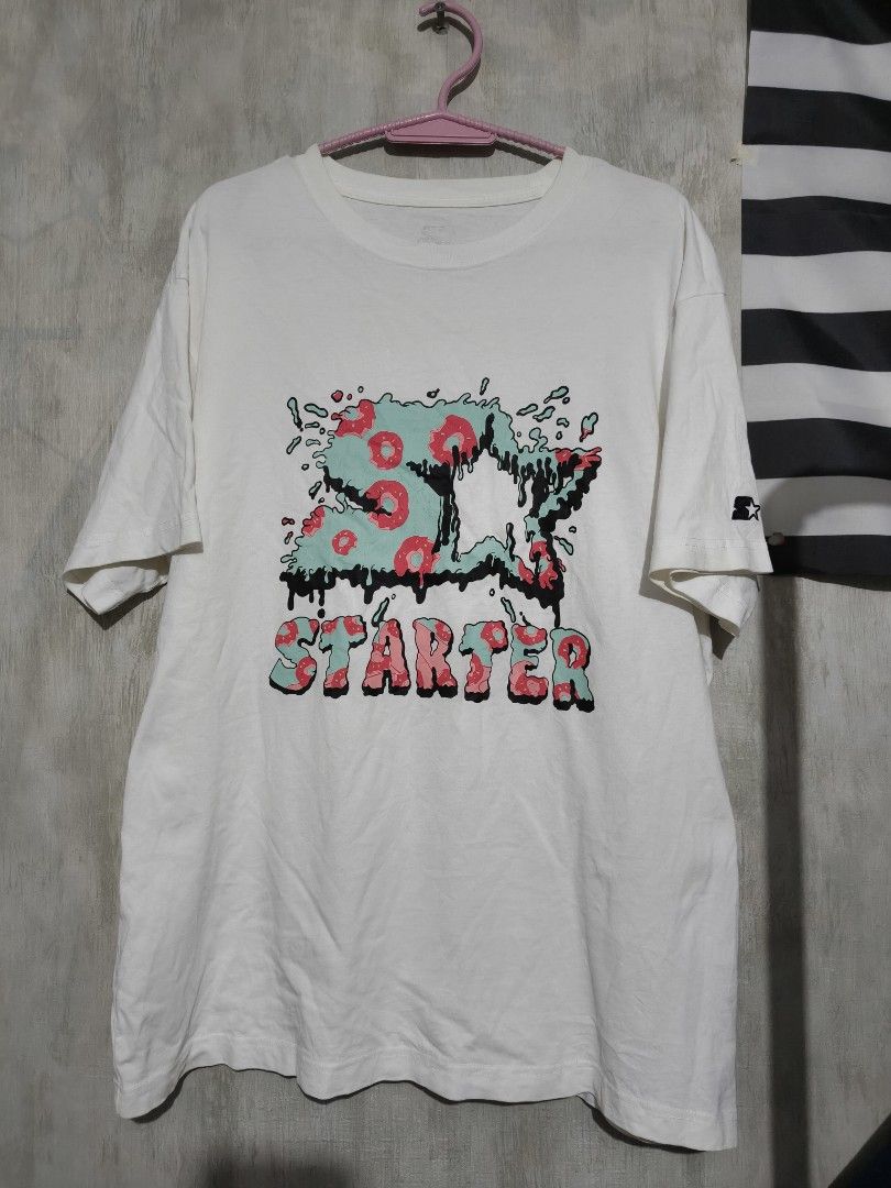 Starter Black Label Graphic T-Shirt (Category: Tshirts & Polo Shirts ) located in Baguio. Submitted by fordaluvofthrift2600 (Listing ID 1466169663, Image 1). Description: - Brand: Starter Black Label - Color: White with pink and teal graphic - Size: Medium (tagged at collar) - Design: Large drip-style front print & sleeve logo patch - Fit: Regular fit, short sleeves, crew neck - Material: 100% Cotton.