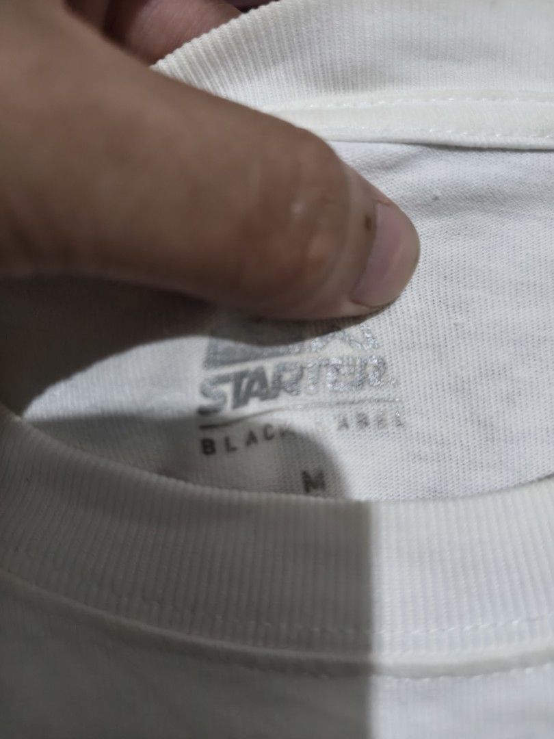 Starter Black Label Graphic T-Shirt (Category: Tshirts & Polo Shirts ) located in Baguio. Submitted by fordaluvofthrift2600 (Listing ID 1466169663, Image 2). Description: - Brand: Starter Black Label - Color: White with pink and teal graphic - Size: Medium (tagged at collar) - Design: Large drip-style front print & sleeve logo patch - Fit: Regular fit, short sleeves, crew neck - Material: 100% Cotton.