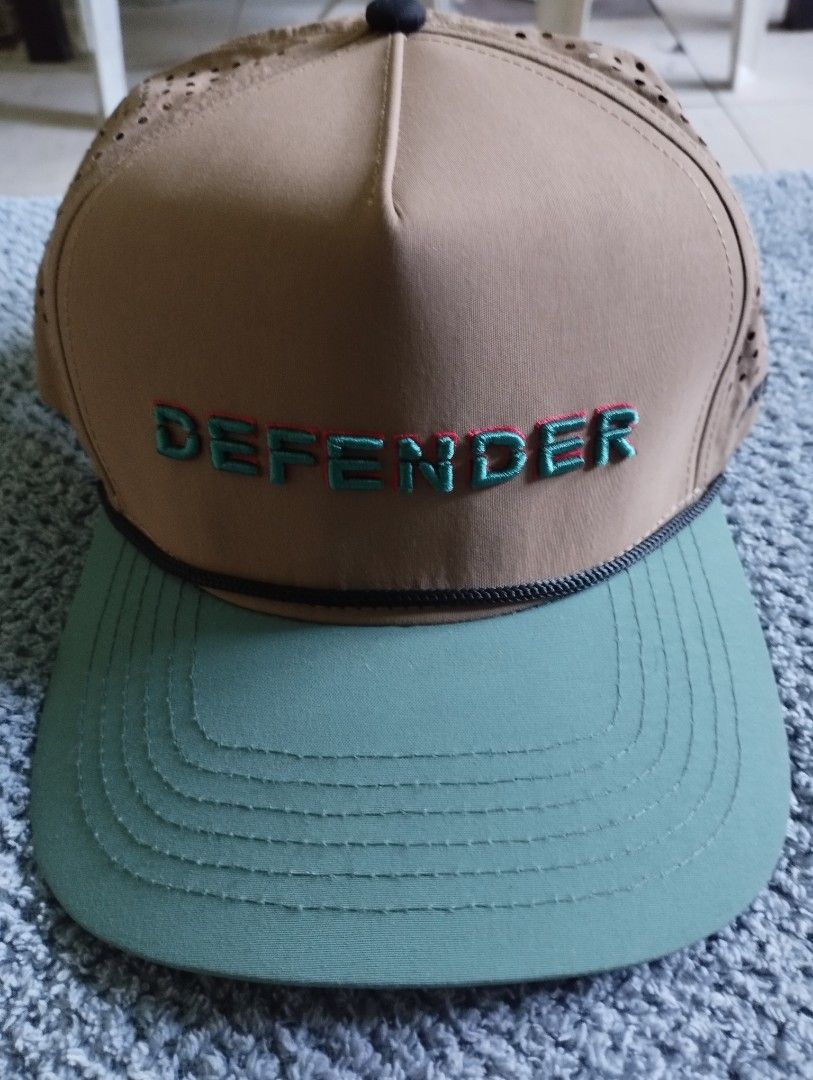 Staunch x Land Rover Defender Snapback Cap (Category: Caps & Hats) located in Manila. Submitted by happycaps (Listing ID 1466179292, Image 1). Description: - Brand: Staunch Outfitters - Style: Perforated cap with snapback closure - Colors: Tan crown, green brim, and vibrant pink under-brim - Details: Embroidered Land Rover Defender text on the front, side branding, and a red logo tag at the back - Fit: Adjustable plastic snapback - Condition: Exc
