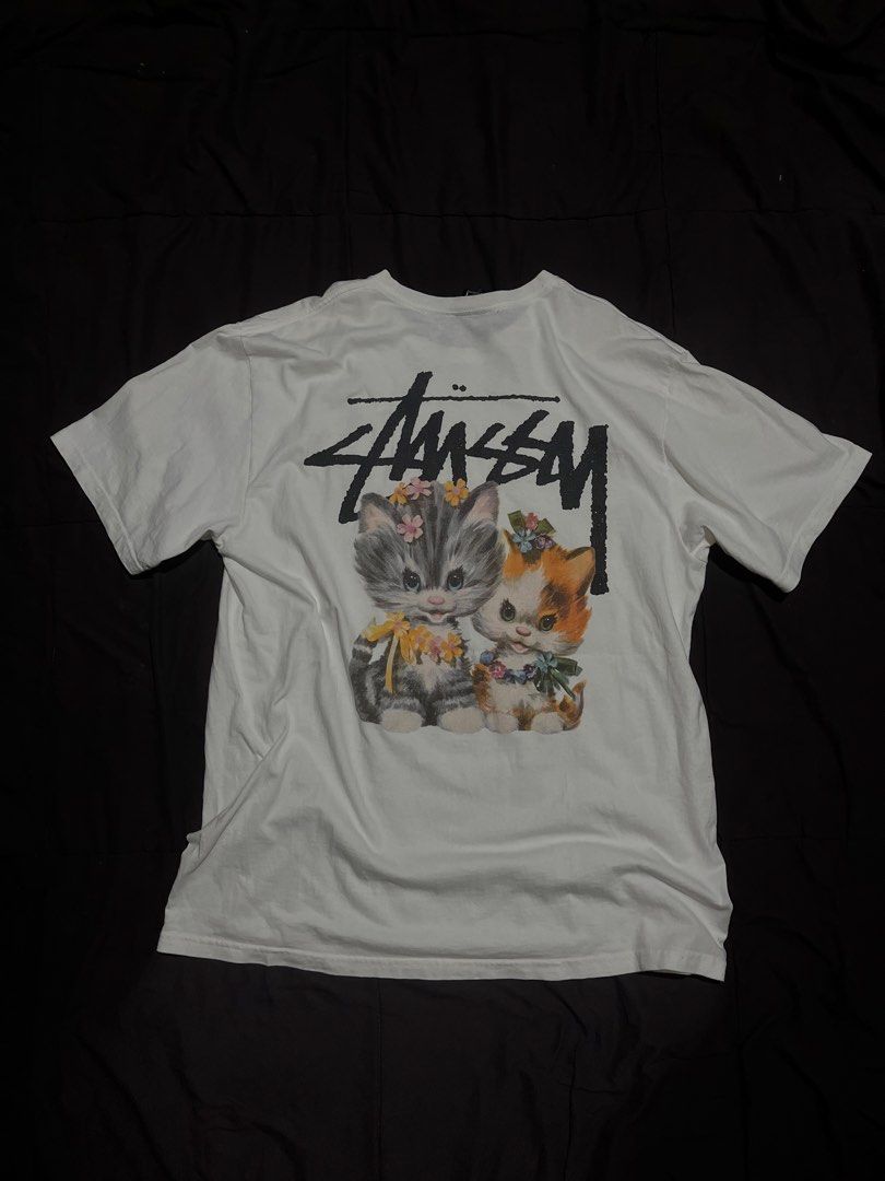 Stussy Kittens Flower Graphic White Tee (Category: Tshirts & Polo Shirts ) located in Davao. Submitted by bothwiseph (Listing ID 1466303582, Image 1). Description: - Brand: Stussy - Color: White - Fit: Comfortable cotton body with tagged collar - Design: Small front chest logo and large kitten with flowers graphic on the back - Style: Classic streetwear piece, perfect for casual wear.