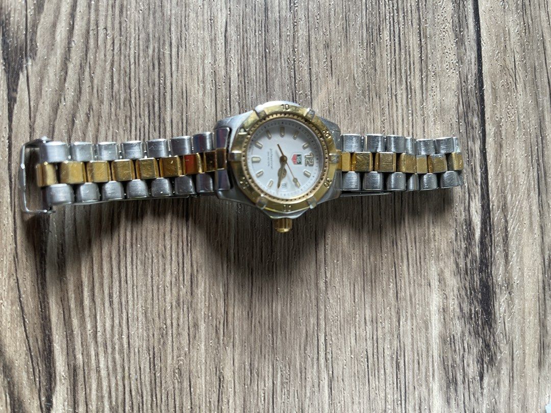 TAG Heuer Professional Two-Tone Watch (Category: Luxury Watches) located in Taguig. Submitted by sellall37207 (Listing ID 1466158939, Image 1). Description: - Brand: TAG Heuer Professional Quartz Watch - Dial: White dial with bold 12 o'clock Arabic numeral and date window - Bezel: Rotating bezel with gold-tone markers and matching gold-finish crown - Band: Two-tone steel and gold-plated bracelet - Condition: Visible signs of wear on the metal lin