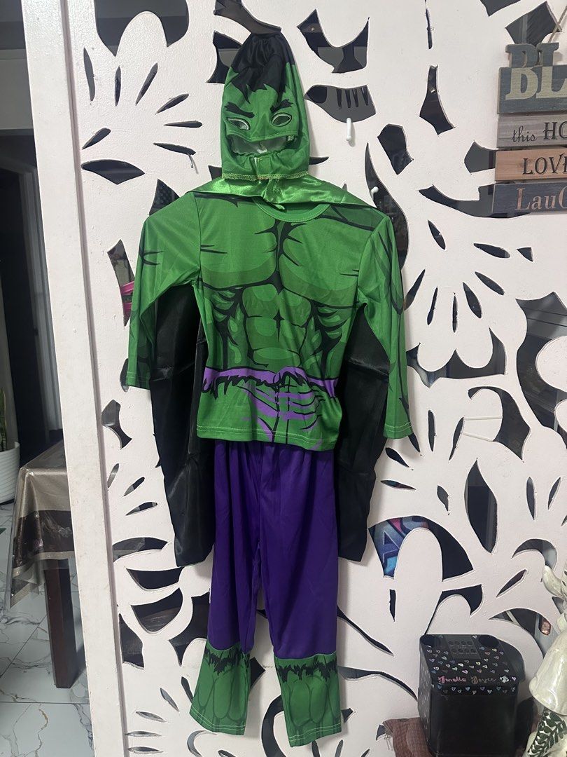 The Hulk Costume Set halloween (Category: Babies & Kids Fashion) located in Manila. Submitted by jentistwah (Listing ID 1466186510, Image 2). Description: Complete Hulk superhero costume for kids aged 5 to 7 years old. Package includes a green mask, muscle-print long sleeve top, matching purple pants with green hem details, and a green cape featuring a large Hulk graphic on the back. Made from lightweight costume material. Great option for partie
