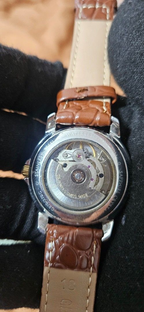Tissot Automatic G270/370G Watch (Category: Men's Watches) located in Santa Maria. Submitted by rommelmateo (Listing ID 1466309500, Image 2). Description: - Brand: Tissot Swiss Automatic Watch - Dial: Textured white dial with Roman numerals and a date window at 3 o'clock - Design: Gold fluted bezel, stainless steel case, and gold crown - Movement: 25 jewels automatic movement visible through the exhibition case back - Strap: Genuine brown leather