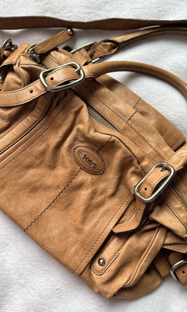 Tod's Brown Leather Shoulder Bag (Category: Luxury Bags & Wallets) located in Quezon City. Submitted by shane_blueraee (Listing ID 1466279519, Image 2). Description: Preloved 🌟 Tod’s Brown Leather Shoulder Bag Genuine Italian leather Warm tan brown Hardware: Silver-tone with exterior buckle strap details Interior: Fabric-lined with a zippered pocket stamped 'Made in Italy' Inclusion: adjustable longer shoulder strap Condition: with leather stain