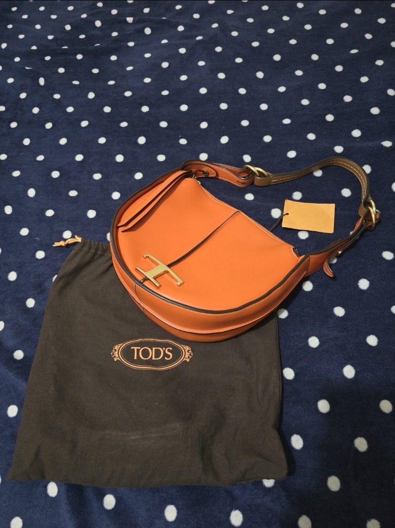 Tod's T Timeless Leather Orange Shoulder Bag (Category: Luxury Bags & Wallets) located in Pasig City. Submitted by litinpink (Listing ID 1466238654, Image 1). Description: - Brand: Tod's (Made in Italy) - Color: Bright orange with gold-tone hardware - Material: Premium leather - Style: Curved saddle shape with structured handle - Closure: Top zip closure - Interior: Clean lining with inner pocket and Tod's leather logo patch - Inclusions: Origina