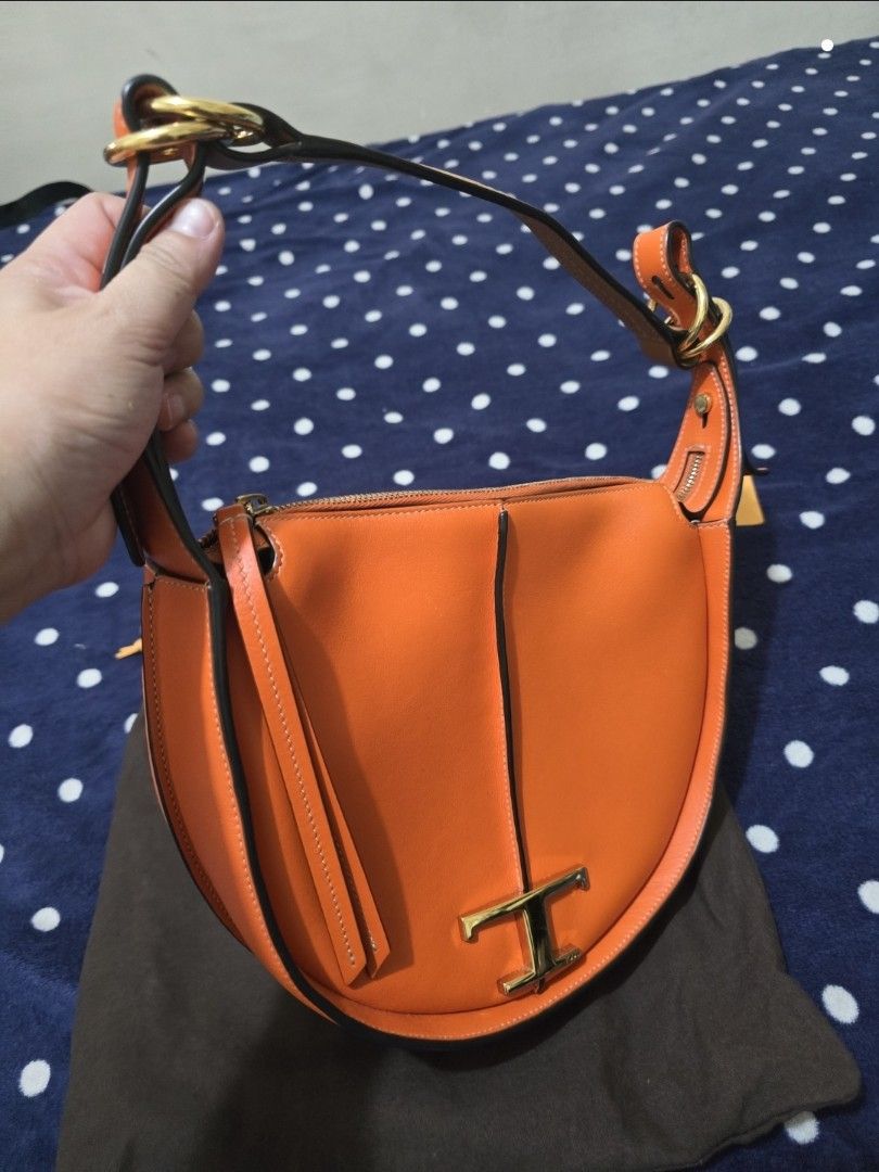 Tod's T Timeless Leather Orange Shoulder Bag (Category: Luxury Bags & Wallets) located in Pasig City. Submitted by litinpink (Listing ID 1466238654, Image 2). Description: - Brand: Tod's (Made in Italy) - Color: Bright orange with gold-tone hardware - Material: Premium leather - Style: Curved saddle shape with structured handle - Closure: Top zip closure - Interior: Clean lining with inner pocket and Tod's leather logo patch - Inclusions: Origina