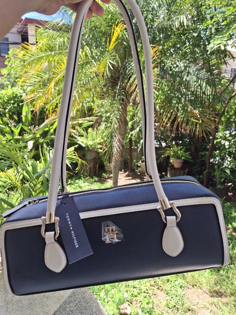 Tommy Hilfiger Shoulder Bag (Category: Shoulder Bags) located in Manila. Submitted by bubuamponin (Listing ID 1466184238, Image 1). Description: - Color: Navy blue with white piping - Hardware: Gold-tone with metallic front logo - Closure: Secure zip top - Straps: Comfortable long straps - Condition: Brand new with hanging brand tag attached - Design: Clean, structured, and classic rectangular shape.