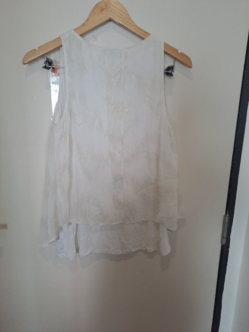 White sleevesless (Category: Sleeveless) located in Manila. Submitted by joanbalde39643 (Listing ID 1466248956, Image 2). Description: This is a white V-neck sleeveless blouse featuring an elegant asymmetrical layered overlay and a subtle jacquard-style textured pattern. The relaxed, flowy silhouette makes it highly versatile for layering under blazers or pairing with chic casual pieces..