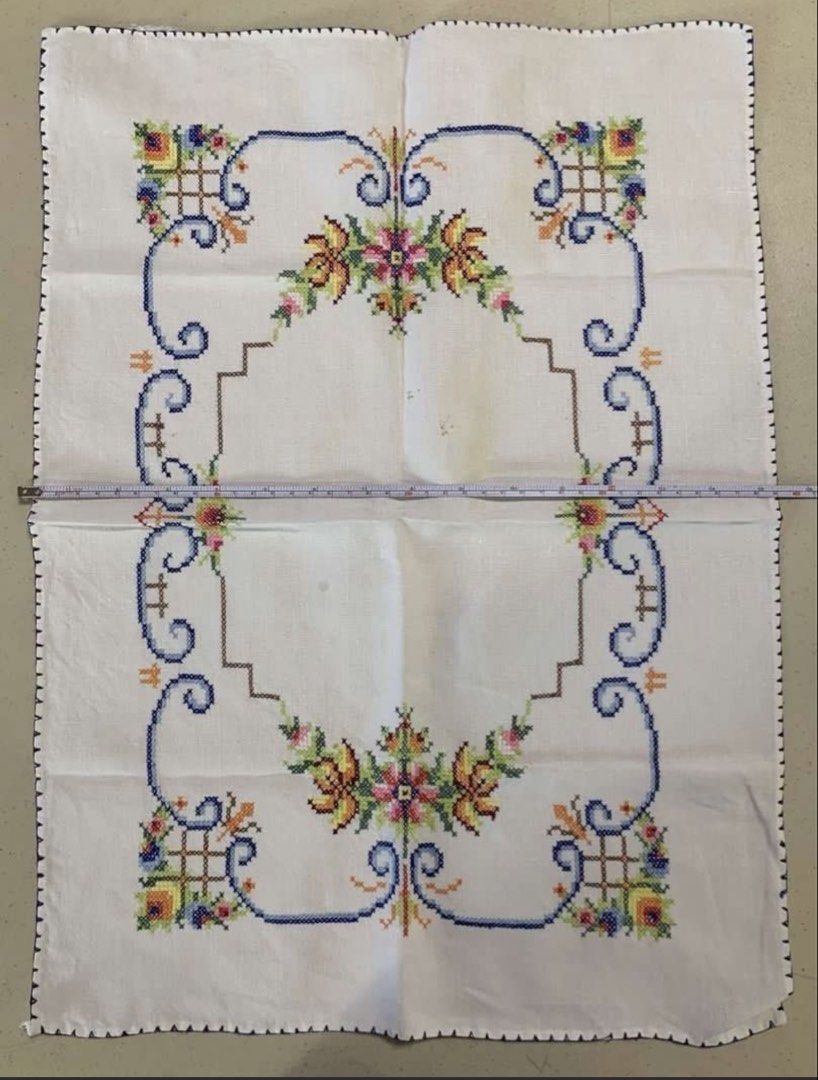 Vintage Hand-Embroidered Cross Stitch Table Runner (Category: Table Linen & Textiles) located in Quezon City. Submitted by meggoquingco (Listing ID 1466174784, Image 2). Description: - Hand-embroidered cross-stitch textile piece - Size: Approximately 39 cm x 52 cm - Design: Colorful floral motifs (yellow, pink, green) with intricate blue and brown borders - Finish: Scalloped dark blue edge all around - Flaws: A couple of faint yellowish marks nea