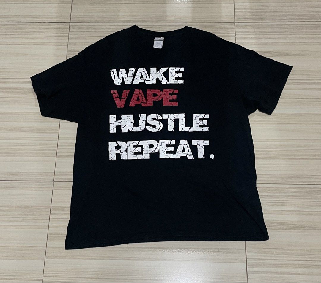 Wake Vape Hustle Repeat Black T-Shirt (Category: Tshirts & Polo Shirts ) located in Legazpi City. Submitted by scrapped.gems (Listing ID 1466183445, Image 1). Description: - Color: Classic Black - Design: Distressed graphic print with 'WAKE VAPE HUSTLE REPEAT' text in white and red - Fit: Crew neck, short sleeves, standard fit - Material: Comfortable standard cotton - Style: Casual streetwear graphic tee.