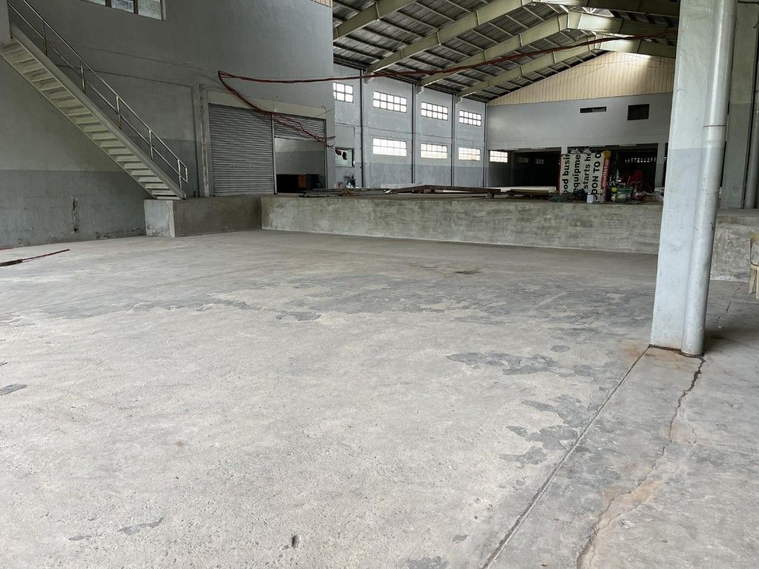 Warehouse with High Ceilings for rent! (Category: Commercial) located in Quezon City. Submitted by santabuko (Listing ID 1466162129, Image 3). Description: - Massive indoor warehouse with high-pitched roof and insulation panels - Durable concrete flooring throughout the entire space - Ample natural light from upper and lower wall windows - Secure entrance featuring large roll-up shutter doors and grated gates - Built-in staircase leading to an up