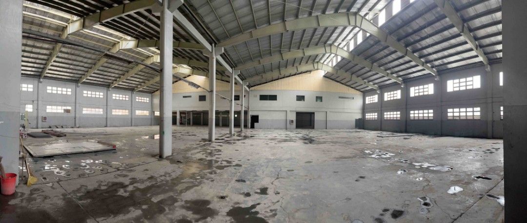 Warehouse with High Ceilings for rent! (Category: Commercial) located in Quezon City. Submitted by santabuko (Listing ID 1466162129, Image 1). Description: - Massive indoor warehouse with high-pitched roof and insulation panels - Durable concrete flooring throughout the entire space - Ample natural light from upper and lower wall windows - Secure entrance featuring large roll-up shutter doors and grated gates - Built-in staircase leading to an up