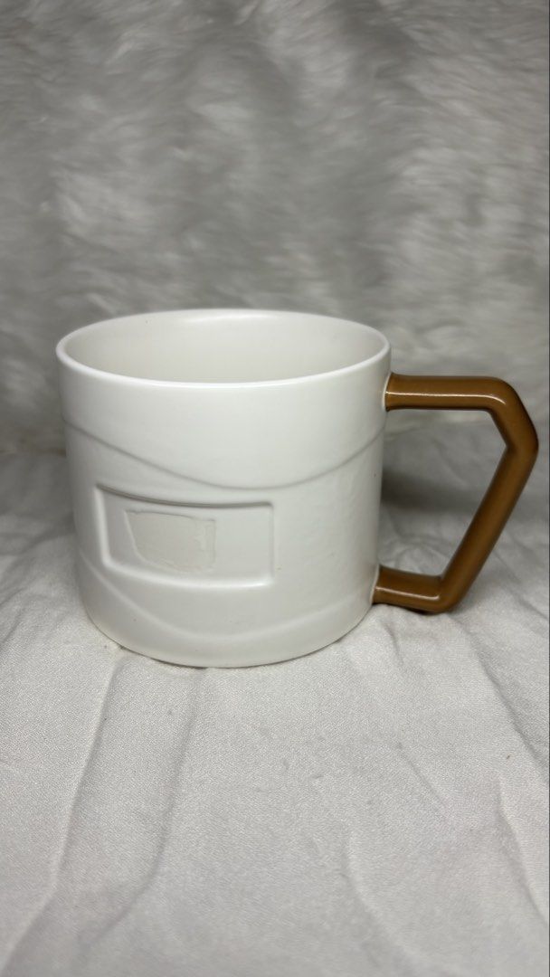 White Ceramic Mug with Brown Angular Handle (Category: Coffee & Tea Tableware) located in Manila. Submitted by mug.aras (Listing ID 1466313711, Image 1). Description: White ceramic coffee cup featuring a unique embossed design and a modern contrast brown geometric handle. Sturdy, clean, and perfect for your daily coffee or tea..