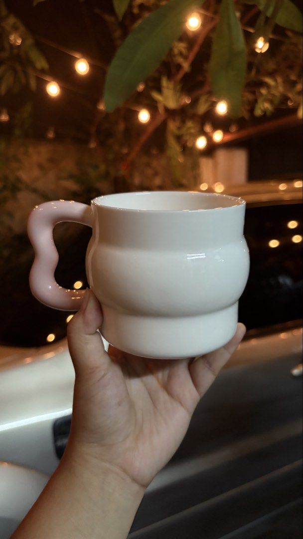 White ceramic mug with pink wavy handle (Category: Coffee & Tea Tableware) located in Manila. Submitted by mug.aras (Listing ID 1466313435, Image 1). Description: White ceramic coffee mug with a glossy finish and a cute wavy pink handle. Thick, rounded body and great for your daily coffee or tea. In excellent, chip-free condition!.