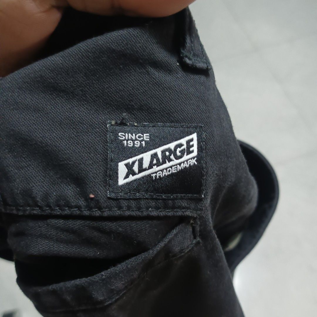 Xlarge Black Workwear Pants Size 32 (Category: Trousers) located in Alaminos. Submitted by andreid12 (Listing ID 1466287561, Image 3). Description: - Brand: Xlarge - Size: 32 (Waistband tag) - Material: Sturdy cotton twill with cream patterned inner lining - Fit: Straight leg cut - Design: Big white Xlarge logo printed on back right leg, woven brand label on back pocket - Closure: Standard button and zip fly.