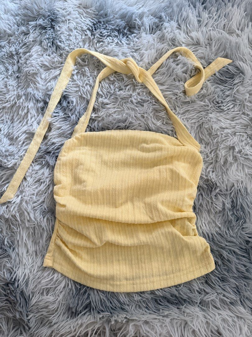 Yellow Ribbed Halter Top with Tie Straps (Category: Sleeveless) located in Legazpi City. Submitted by chindecluttrs (Listing ID 1466201552, Image 1). Description: - Color: Soft yellow - Material: Stretchy ribbed fabric with vertical texture - Design: Halter neck with adjustable self-tie straps and open back - Fit: Cropped length, curved hem, and flattering side ruching.