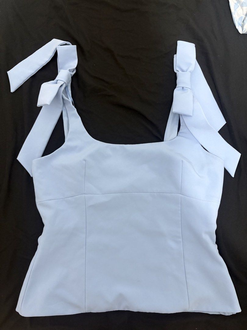 Zara Light Blue Tank Top with Bow Straps (Category: Sleeveless) located in Manila. Submitted by gela__444 (Listing ID 1466326504, Image 1). Description: - Brand: Zara - Size: L (EUR/USA L, MEX 30) - Color: Light blue - Design: Square neckline with tie-up bow straps and structured front - Closure: Convenient side zipper .