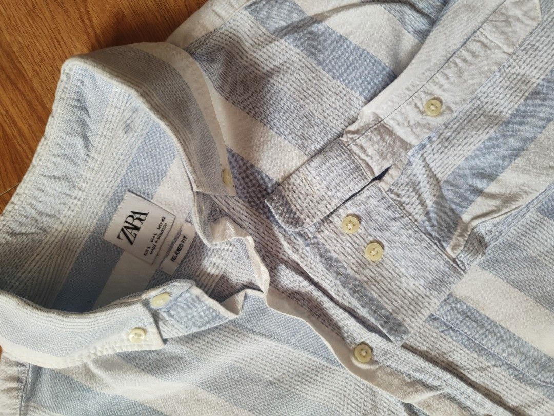 Zara Men's Light Blue Striped Button-Down Shirt (Category: Tshirts & Polo Shirts ) located in San Pablo. Submitted by greatfindsspc (Listing ID 1466207593, Image 2). Description: Add a crisp, breezy staple to your wardrobe with this Zara Men's striped button-down shirt. Featuring a relaxed fit with alternating thick and textured pin-stripes in light blue and white, this lightweight shirt is perfect for casual outings, beach days, or smart-casual 