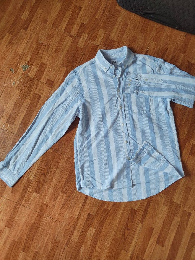 Zara Men's Light Blue Striped Button-Down Shirt (Category: Tshirts & Polo Shirts ) located in San Pablo. Submitted by greatfindsspc (Listing ID 1466207593, Image 1). Description: Add a crisp, breezy staple to your wardrobe with this Zara Men's striped button-down shirt. Featuring a relaxed fit with alternating thick and textured pin-stripes in light blue and white, this lightweight shirt is perfect for casual outings, beach days, or smart-casual 