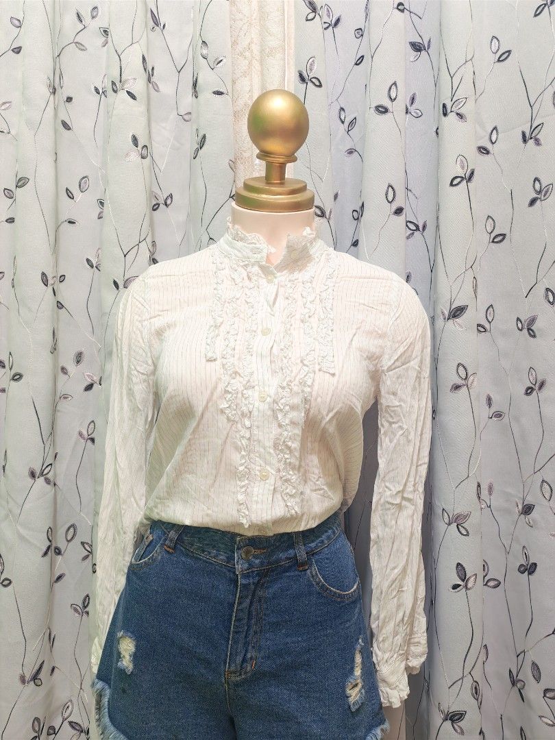 ZARA Striped Ruffle High Neck Blouse (Category: Blouses) located in Caloocan City. Submitted by _misskaye (Listing ID 1466161282, Image 1). Description: - Brand: ZARA - Size: XS - Color: White with subtle blue vertical stripes - Details: High ruffled neck, button-down front with vertical ruffle trims, long sleeves - Material: Lightweight fabric - Origin: Made in Turkey - Condition/Use: Great for layering or wearing solo to work or casual outings.