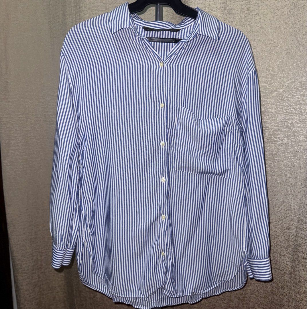 Zara Trafaluc Striped Button Down Shirt (Category: Shirts) located in Manila. Submitted by she_alice (Listing ID 1466326387, Image 2). Description: - Brand: Zara Trafaluc - Size: Small (S) runs big - Color: Classic blue and white stripes - Fit: Relaxed fit - Details: Long sleeves, button-down front, single chest pocket - - Condition: Excellent, no noticeable signs of use. -Super pretty in actual. 💬 Feel free to message me for any questions 🛵 Ca