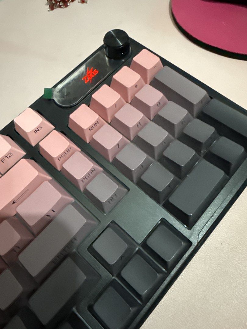 Zeus V102 Mechanical Keyboard Gradient Pink Grey (Category: Computer Keyboard) located in Muntinlupa City. Submitted by itsraas (Listing ID 1466297504, Image 2). Description: - Model: Zeus V102 Mechanical Keyboard - Condition: Tested and 100% fully working - Design: Stylish gradient keycaps transitioning from pink to dark grey with a solid black frame casing - Layout: Compact design complete with a numeric keypad section - Extra Feature: Handy ro