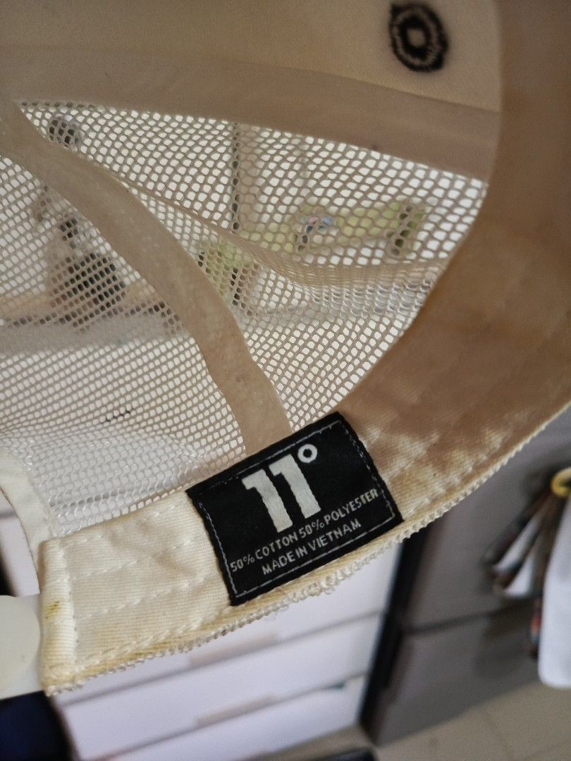 11 Degrees White Trucker Cap (Category: Caps & Hats) located in Irosin. Submitted by whanchore55263 (Listing ID 1466382439, Image 3). Description: - Brand: 11 Degrees - Color: White with classic bold logo - Material: Cotton and polyester blend (Made in Vietnam) - Features: Breathable mesh back panel and adjustable snapback closure - Condition: Shows yellowing and stains around the inner sweatband and brim edges due to wear - Perfect for casual st