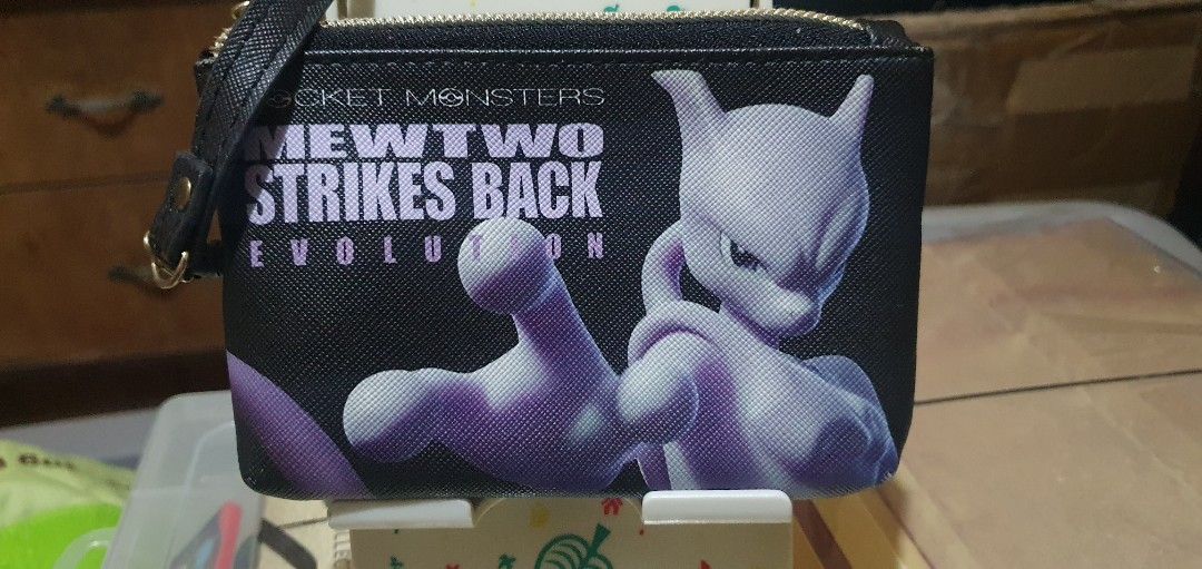 2019 Mewtwo Strikes Back Evolution Pass Case (Category: Character Goods) located in Quezon City. Submitted by collectionneursonline88 (Listing ID 1466402651, Image 1). Description: - Authentic Pokémon Mewtwo Strikes Back Evolution merchandise - Material: Premium black textured faux leather with gold-tone zipper hardware - Design: Purple Mewtwo graphic print on front and clear ID window with circular Pocket Monsters logo insert on back - Functiona