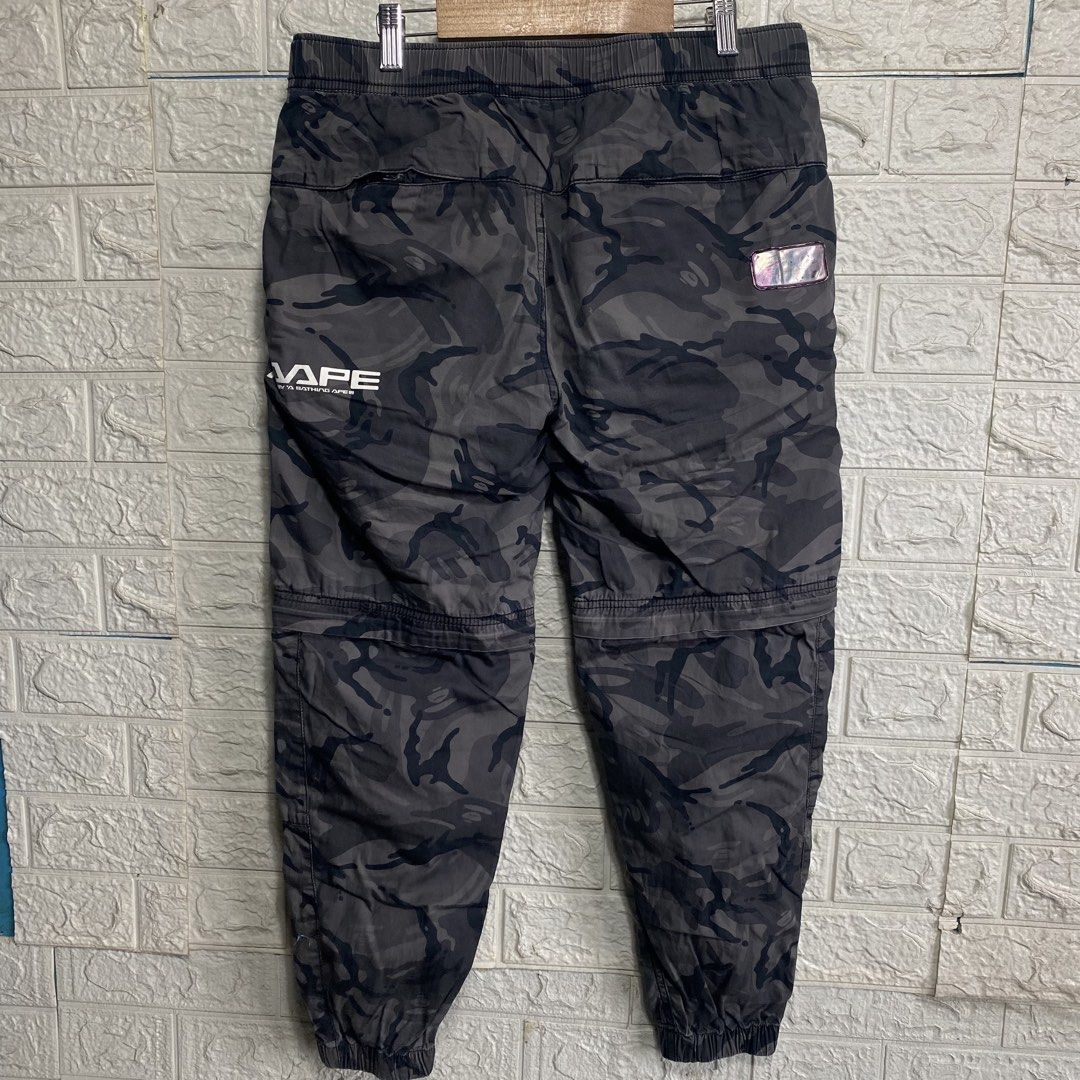 Aape By A Bathing Ape Camo Cargo Pants (Category: Joggers) located in Naga. Submitted by thesource4400 (Listing ID 1466477402, Image 2). Description: - Brand: Aape - Color/Pattern: Grey Camo - Fit/Details: Elastic waistband, built-in belt, and cuffed ankles - Design: Bold graphic text on right leg with front and back branded patches - Storage: Multiple utility pockets - Condition: Solid overall, perfect for daily streetwear rotation.