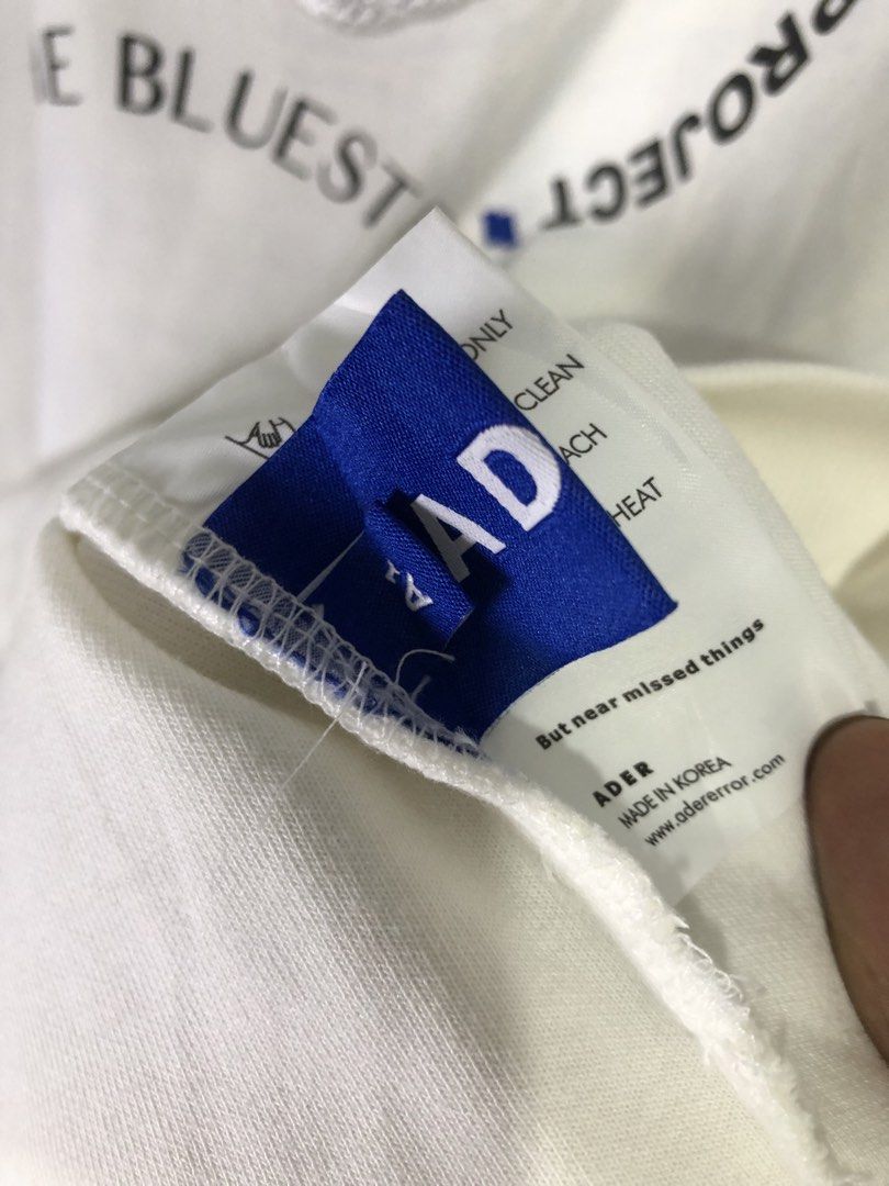 Ader Error x Maison Kitsune Blue Fox Project Sweatshirt (Category: Coats, Jackets and Outerwear) located in Quezon City. Submitted by clarizedeo09960 (Listing ID 1466502689, Image 3). Description: - Brand: Ader Error x Maison Kitsune Collaboration - Color: White - Material: Premium cotton - Design: Large embroidered blue fox graphic with circular typography - Details: Ribbed collar, cuffs, hem, and iconic blue brand tag - Size: Tagged A1 - Origin