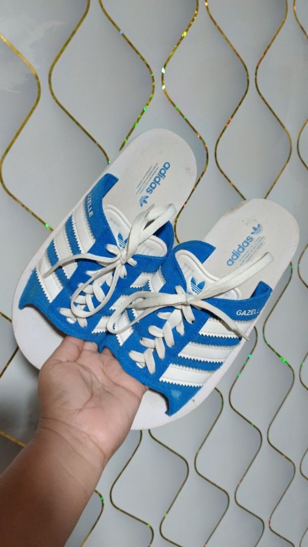 Adidas Gazelle Slides Blue White (Category: Slippers & Slides) located in Manila. Submitted by zariyah.1986 (Listing ID 1466439465, Image 3). Description: - Item: Adidas Gazelle slides - Color: Blue and white with classic three stripes and decorative laces - Size: US 7 / UK 6 / FR 39 / JP 245 / CHN 240 - Material: Suede upper with white footbed - Details: Adidas branding and Gazelle text on the side, made in Vietnam (Date code: 05/24) - Condition