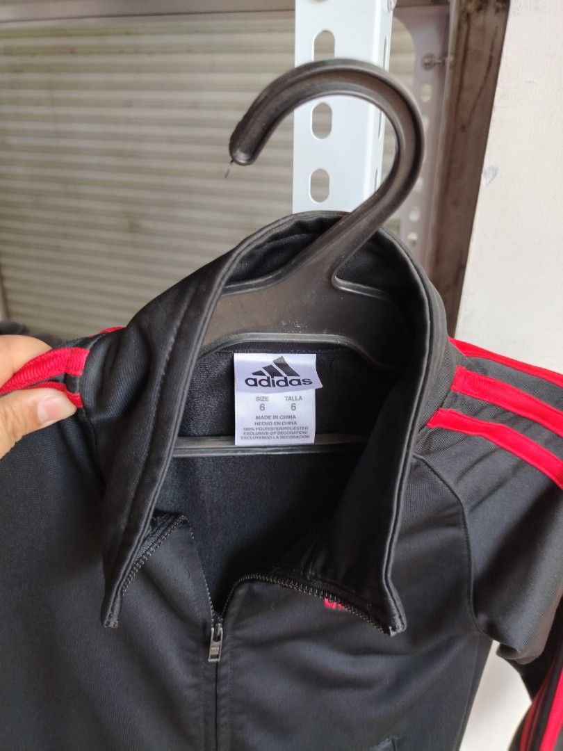 Adidas Kids Black Red Track Jacket Size 6 (Category: Babies & Kids Fashion) located in General Tinio. Submitted by crisantacruz (Listing ID 1466473636, Image 3). Description: - Brand: Adidas - Color: Black with bright red stripes and red embroidered logo - Size: 6 - Material: 100% polyester - Features: Full zip closure, two front hand pockets, ribbed cuffs and hem - Condition: Excellent pre-loved condition - Mode of Payment: GCash - Shipping: Shi