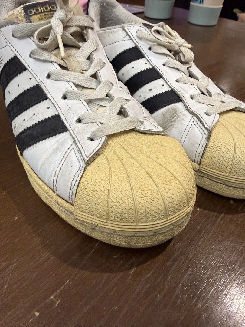 Adidas Superstar White Black Men US 7 (Category: Sneakers) located in Quezon City. Submitted by nsseller (Listing ID 1466460118, Image 2). Description: - Brand: Adidas Superstar - Color: White and Black - Size: US 7 / UK 6.5 / FR 40 / JP 250 / CHN 245 - Features: Classic shell toe design with gold lettering on the side and tongue, Made in Indonesia - Condition: Pre-owned with regular wear, minor scuffs, creasing, and natural yellowing on the rubb
