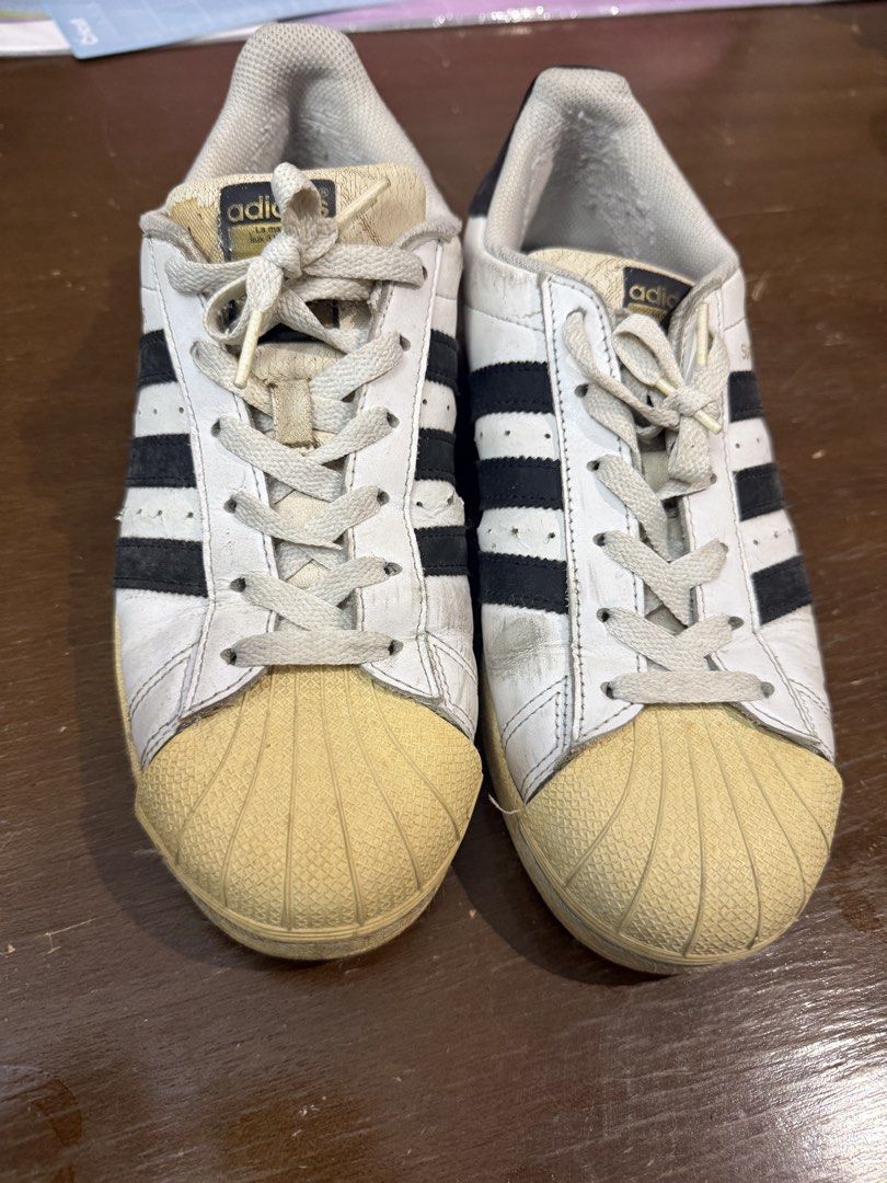 Adidas Superstar White Black Men US 7 (Category: Sneakers) located in Quezon City. Submitted by nsseller (Listing ID 1466460118, Image 1). Description: - Brand: Adidas Superstar - Color: White and Black - Size: US 7 / UK 6.5 / FR 40 / JP 250 / CHN 245 - Features: Classic shell toe design with gold lettering on the side and tongue, Made in Indonesia - Condition: Pre-owned with regular wear, minor scuffs, creasing, and natural yellowing on the rubb