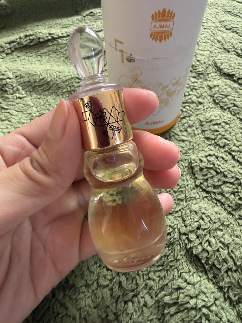 Ajmal - Miss Universe (Category: Fragrance & Deodorants) located in Manila. Submitted by julianna_pm (Listing ID 1466345834, Image 2). Description: Ajmal concentrated perfume oil in an ornate glass bottle. Gold cap with geometric patterns and crystal-like stopper. Includes original white cylindrical packaging with gold branding and graphics. Fragrance oil level is clearly visible inside the bottle. Traditional Middle Eastern attar style. Stored p